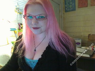 A 320x240 pixel webcam photo of Sunny Crittenden circa 2010. She has long, straight, pink hair and pink glasses.