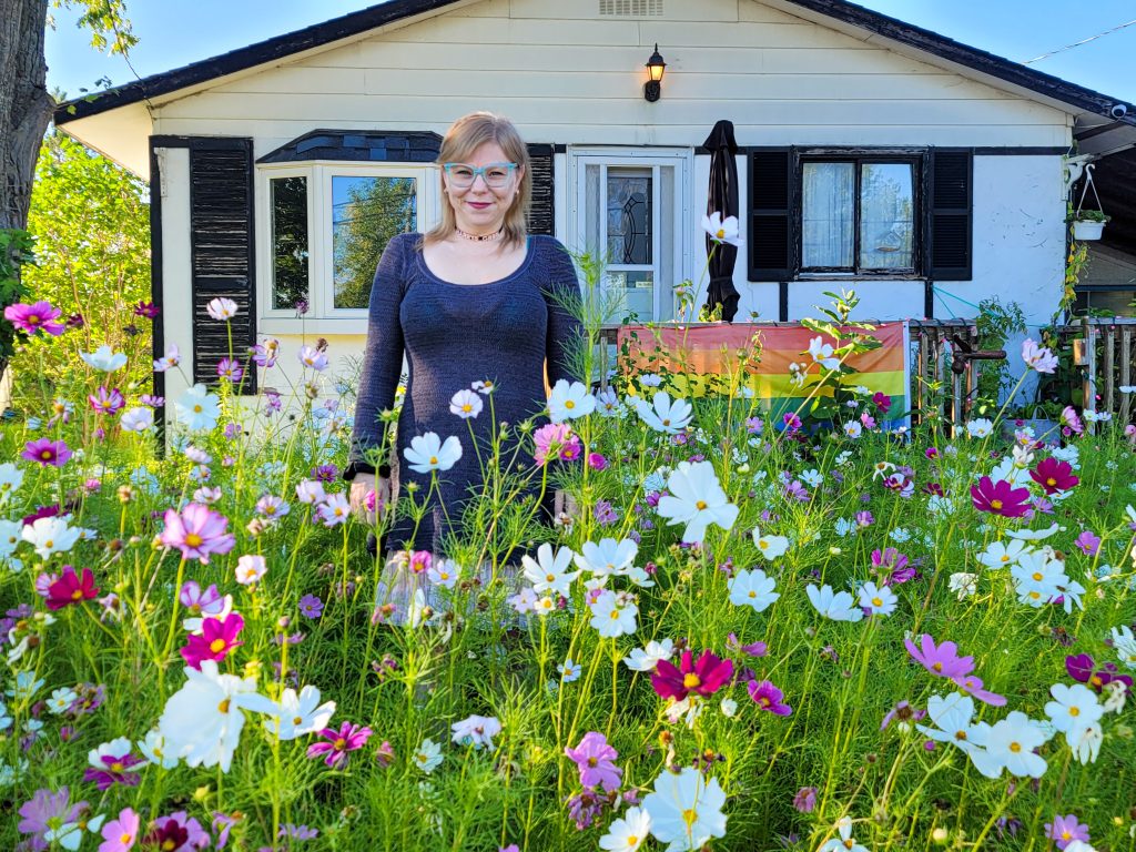 A photo of Sunny Crittenden standing in the wildflower garden outside of her home, taken in August 2022.